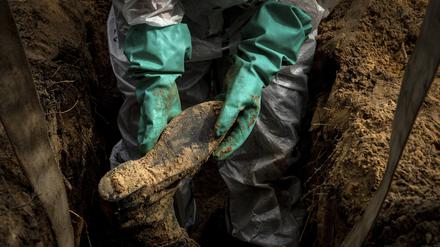 Ein Mitarbeiter der Rettungsdienste hält das Bein eines Zivilisten während einer Exhumierung im kürzlich zurückeroberten Gebiet von Isjum in der Ukraine.