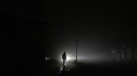 Eine Frau spaziert durch das dunkle Stadtzentrum von Kiew.