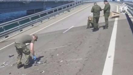 Das vom russischen Ermittlungskomitee via AP veröffentlichte Videostandbild zeigt Ermittler an einer beschädigten Teil einer Automobilverbindung der Krim-Brücke, die das russische Festland mit der Halbinsel Krim verbindet.