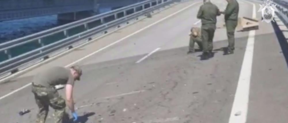 Das vom russischen Ermittlungskomitee via AP veröffentlichte Videostandbild zeigt Ermittler an einer beschädigten Teil einer Automobilverbindung der Krim-Brücke, die das russische Festland mit der Halbinsel Krim verbindet.