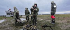 Rekruten bereiten ihre Waffen vor, während ein Ausbilder sie bei einer militärischen Ausbildung auf einem Schießplatz in der Region Wolgograd beobachtet. 