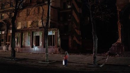 Passanten betrachten ein beschädigtes Gebäude in der ukrainischen Stadt Saporischschja.