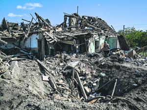 Ein Krater vor einem Haus in Saporischschja, Ukraine, das durch russischen Beschuss zerstört wurde.