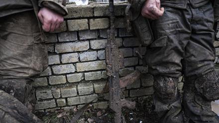 Ein mit Schlamm verschmutztes Gewehr ist vor ukrainischen Soldaten zu sehen, die am 8. März von Tranchen von Bachmut zurückkommen.