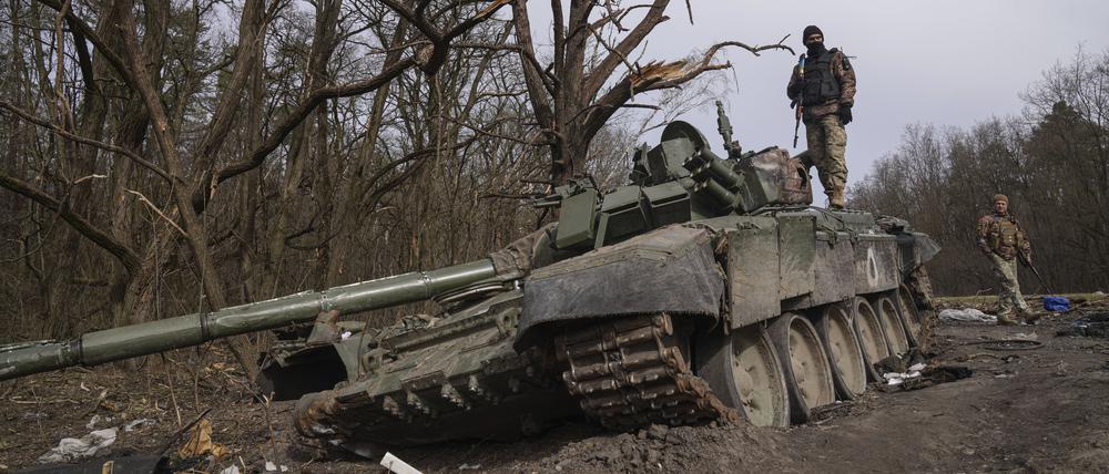Tschernihiw: Ein ukrainischer Soldat steht auf einem zerstörten russischen Panzer.
