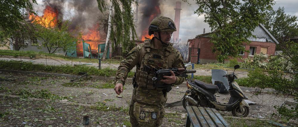 Ein Polizist läuft vor einem brennenden Haus in Wowtschansk, das durch einen russischen Luftangriff zerstört wurde. 