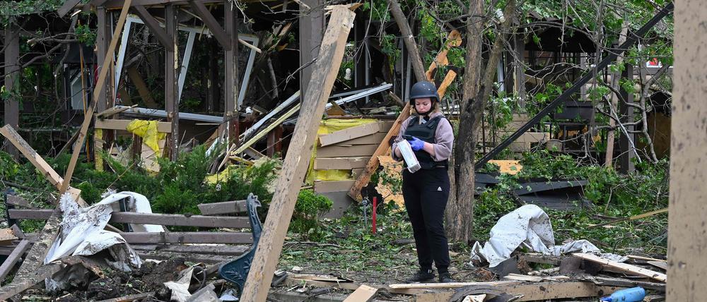 Eine ukrainische Polizistin steht an einem zerstörten Platz im Dorf Cherkaska Lozova.