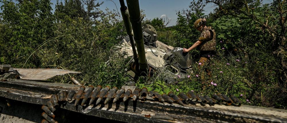Ein ukrainischer Soldat inspiziert einen zerstörten russischen BMP-3-Panzer in der Region Saporischschja, am 21. Juli 2023. Wenige Tage später haben ukrainische Truppen offenbar einen BMP-1-Panzer unbemannt über ein Minenfeld geschickt. 