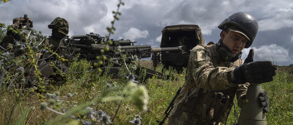 ARCHIV - 14.07.2022, Ukraine, Charkiw: Ein ukrainischer Soldat installiert einen Zünder für eine 155-mm-Artilleriegranate, bevor er mit einer von den USA gelieferten Haubitze des Typs M777 auf russische Stellungen schießt. (zu dpa: «Ukraine soll neue Geschosse für Angriffe über Grenze nutzen können») Foto: Evgeniy Maloletka/AP/dpa +++ dpa-Bildfunk +++