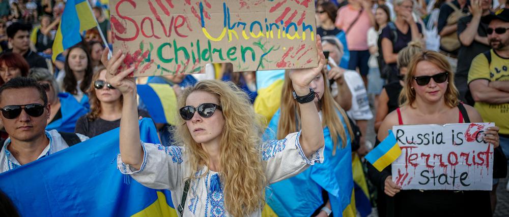 24.08.2023, Berlin: Im Rahmen des Ukrainischen Unabhängigkeitstag demonstrieren Menschen unter dem Motto «UkrainianIndependenceDay» vor dem Brandenburger Tor. Auf einem Plakat steht geschrieben «Save ukrainian children» (dt. rettet ukrainische Kinder). Foto: Kay Nietfeld/dpa +++ dpa-Bildfunk +++