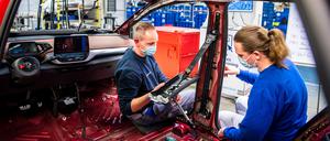 VW-Mitarbeiterinnen und Mitarbeiter werden in einem Trainingsbereich für die Produktion von Elektroautos geschult.