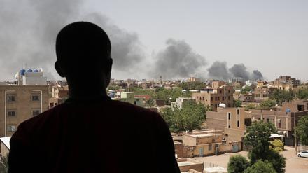 Ein Mann blickt auf die Stadt Khartum, wo schwarzer Rauch aufsteigt.