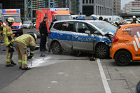 Ein Feuerwehrmann steht nach einem Unfall an einem beschädigten Polizeiauto.
