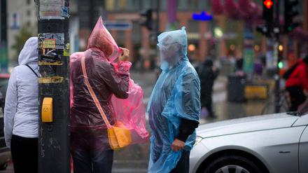 Passanten mit Regenschutzhuellen stehen am Donnerstag (04.10.12) in Berlin auf der Strasse am Potsdamer Platz. 
