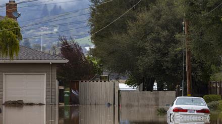 10.03.2023, USA, Watsonville: Ein Auto ist von Hochwasser umgeben.