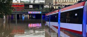 Eine Straßenbahn steht in einer überschwemmten Straße an einer Unterführung in Nürnberg.