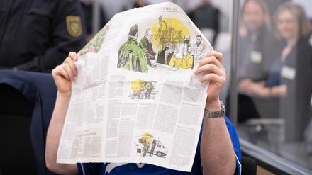 Ein Angeklagter im Prozess um den Juwelenraub im Dresdener Grünen Gewölbe versteckt sich hinter einer Zeitung. 