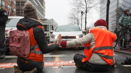 Klimaaktivisten sitzen mit ihren Händen zusammengeklebt auf einer Straße am Potsdamer Platz und wärmen sich ihre Hände mit einem Wärmekissen. Die Berliner Staatsanwaltschaft hat inzwischen 1100 Verfahren (Stand 6. Januar) zu den anhaltenden Aktionen von Klima-Demonstranten auf den Tisch bekommen. (Zu dpa: Hunderte Verfahren bei Justiz nach Blockaden von Klima-Aktivisten) +++ dpa-Bildfunk +++