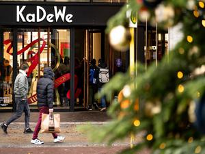 Menschen gehen am verkaufsoffenen Sonntag hinter einem Weihnachtsbaum am Kaufhaus des Westens (KaDeWe) vorbei. 