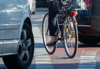 Eine Fahrradfahrerin radelt auf einem Radweg, während Autos rechts abbiegen.