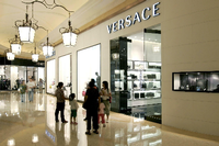 Besucher gehen vor einem Versace-Shop in einem Luxus-Einkaufszentrum in Macao in China.