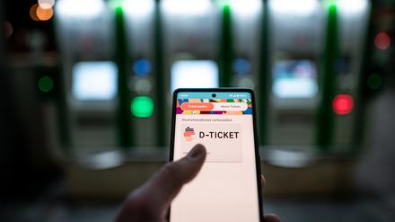 Ein Mann hält ein Mobiltelefon, auf dem das ·D-Ticket· gekauft werden kann, vor Ticketautomaten am Hauptbahnhof Essen in der Hand. (Symbolbild).