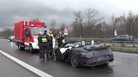 Polizisten stehen an dem Wrack eines Porsches auf der Autobahn 3. Vier Menschen sind bei kurz aufeinander folgenden Unfällen auf der A3 bei Emmerich am Niederrhein ums Leben gekommen - darunter auch ein Ersthelfer. Rettungshubschrauber, Notärzte und Krankenwagen waren den Angaben zufolge im Einsatz.