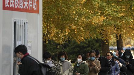 08.11.2022, China, Peking: Menschen mit Gesichtsmasken stehen an, um ihre routinemäßigen COVID-19-Rachenabstriche in einem Coronavirus-Testzentrum in Peking zu erhalten. 