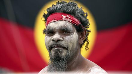 Rauchzeremonie. Stedman Sailor steht am Australia Day mit anderen Mitgliedern der indigenen Bevölkerung Australiens vor der Fahne der Aborigines.