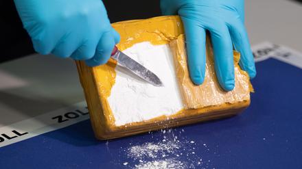Ein Zollbeamter öffnet während einer Pressekonferenz ein Paket mit Kokain, das von den Beamten sichergestellt wurde.