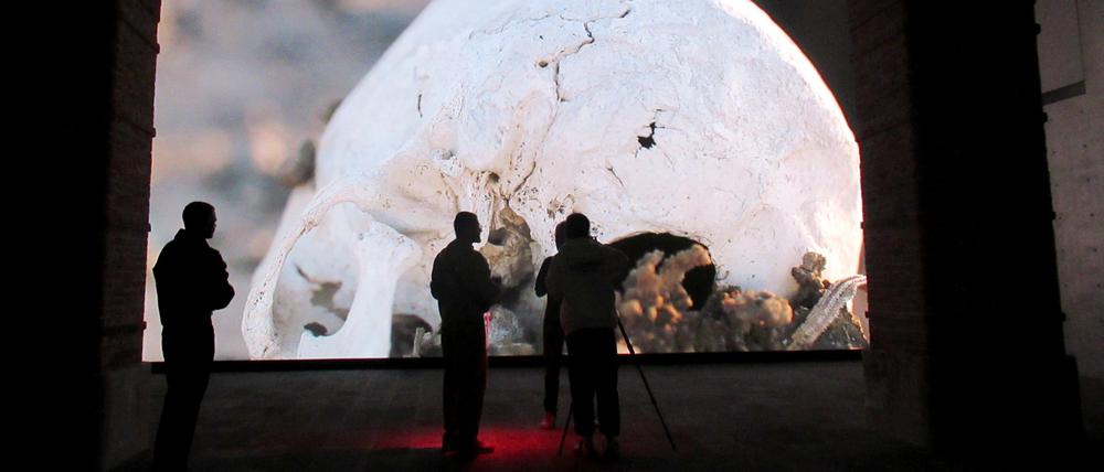 Im Museum Punta della Dogana. Besucher stehen vor dem Werk „Camata“ von Pierre Huyghe. Es zeigt ein menschliches Skelett, um das herum Roboterarme eine Art bizarres Beerdigungsritual verrichten. 