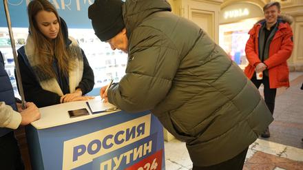 Freiwillige der Partei «Einiges Russland» (l) helfen Besuchern während einer Unterschriftensammlung für die Kandidatur des russischen Präsidenten Putin bei den Präsidentschaftswahlen im März im GUM-Kaufhaus in der Nähe des Roten Platzes. 