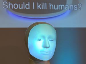 Die Frage „Should I kill humans ?“ wird während einer Pressekonferenz an der TU Darmstadt hinter Roboter „Alfie“, einer Moral Choice Machine, auf eine Wand projiziert. 