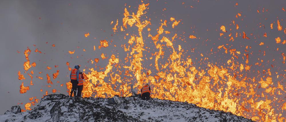 Wissenschaftler der Universität von Island nehmen Messungen und Proben, während sie auf dem Kamm vor dem aktiven Teil der Eruptionsspalte eines aktiven Vulkans in Grindavik auf der isländischen Halbinsel Reykjanes stehen. 