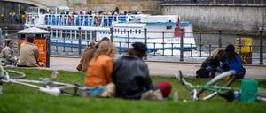 05.04.2024, Berlin: Junge Menschen sitzen bei frühlingshaften Temperaturen am im Monbijoupark am Spreeufer, während im Hintergrund ein Ausflugsschiff vorbeifährt. (zu dpa: «Sommerwetter zieht Berlinerinnen und Berliner nach draußen») Foto: Monika Skolimowska/dpa +++ dpa-Bildfunk +++