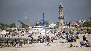 Menschen genießen am Samstag das warme, sonnige Wetter am Ostseestrand von Warnemünde.