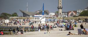 Menschen genießen am Samstag das warme, sonnige Wetter am Ostseestrand von Warnemünde.