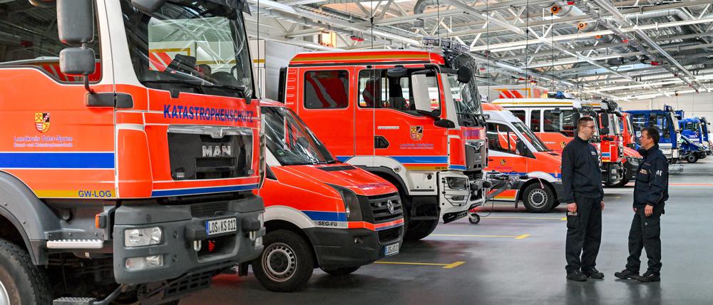 Einsatzkräfte der Feuerwehr stehen in einer Halle mit Fahrzeugen vom Lagezentrum vom Brand- und Katastrophenschutz des Landkreises Oder-Spree.