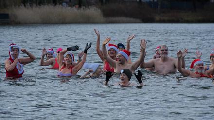 Teilnehmer winken beim  Weihnachts-Eisbaden der Berliner Seehunde 