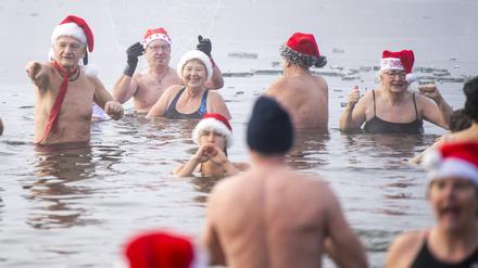 Mitglieder des Vereins „Berliner Seehunde“ baden beim Weihnachtsbaden im Orankesee zwischen Eisschollen. 