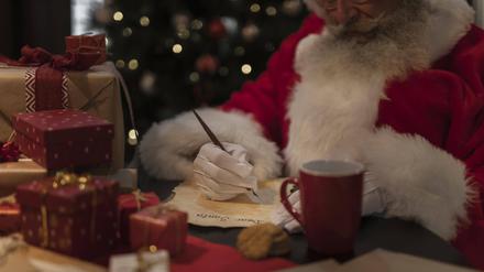 Der Weihnachtsmann schreibt neben Geschenken einen Brief.