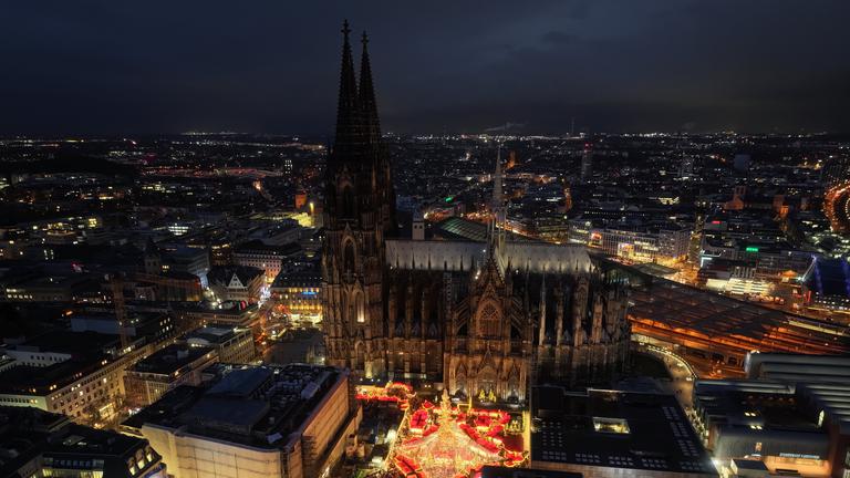 Der Kölner Dom und der Weihnachtsmarkt auf dem Roncalliplatz bei Nacht.
