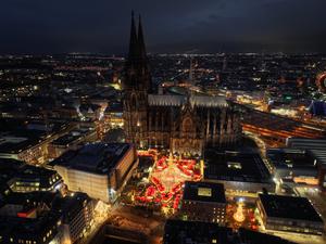 Der Kölner Dom und der Weihnachtsmarkt auf dem Roncalliplatz bei Nacht.