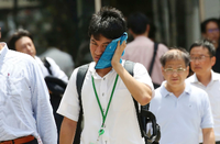 Ein Mann wischt sich den Schweiß aus seinem Gesicht in der sengenden Hitze Tokios.