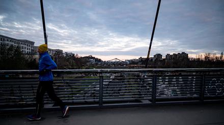 Ein Jogger läuft am frühen Morgen in Berlin über eine Brücke in Prenzlauer Berg.