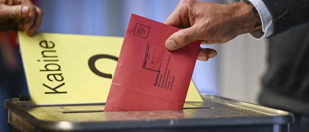 04.01.2023, Berlin: Zum Beginn der Briefwahl für die Wiederholungswahlen am 12. Februar wählt ein Mann im Rathaus Zehlendorf und steckt seine Stimmzettel in einem Briefumschlag für die Briefwahl in die Wahlurne. Foto: Jens Kalaene/dpa +++ dpa-Bildfunk +++