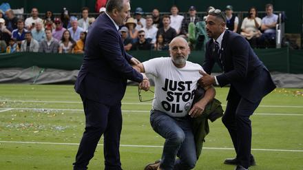 Ein Just Stop Oil-Protestler wird am dritten Tag der Wimbledon-Tennismeisterschaften von Court 18 entfernt.