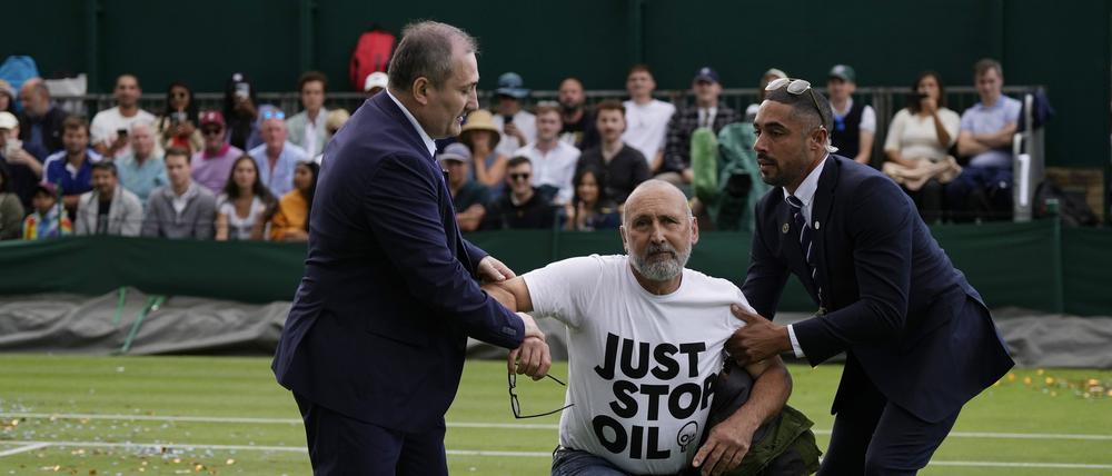 Ein Just Stop Oil-Protestler wird am dritten Tag der Wimbledon-Tennismeisterschaften von Court 18 entfernt.