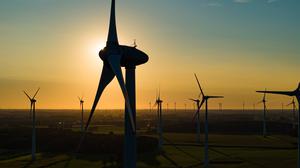Windkraftanlagen sind im Licht der niedrig stehenden Sonne in einem Windpark zu sehen. 