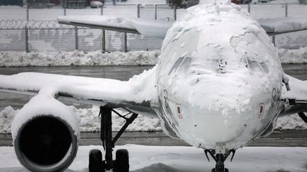 Ein verschneites Flugzeug steht am Flughafen in München.